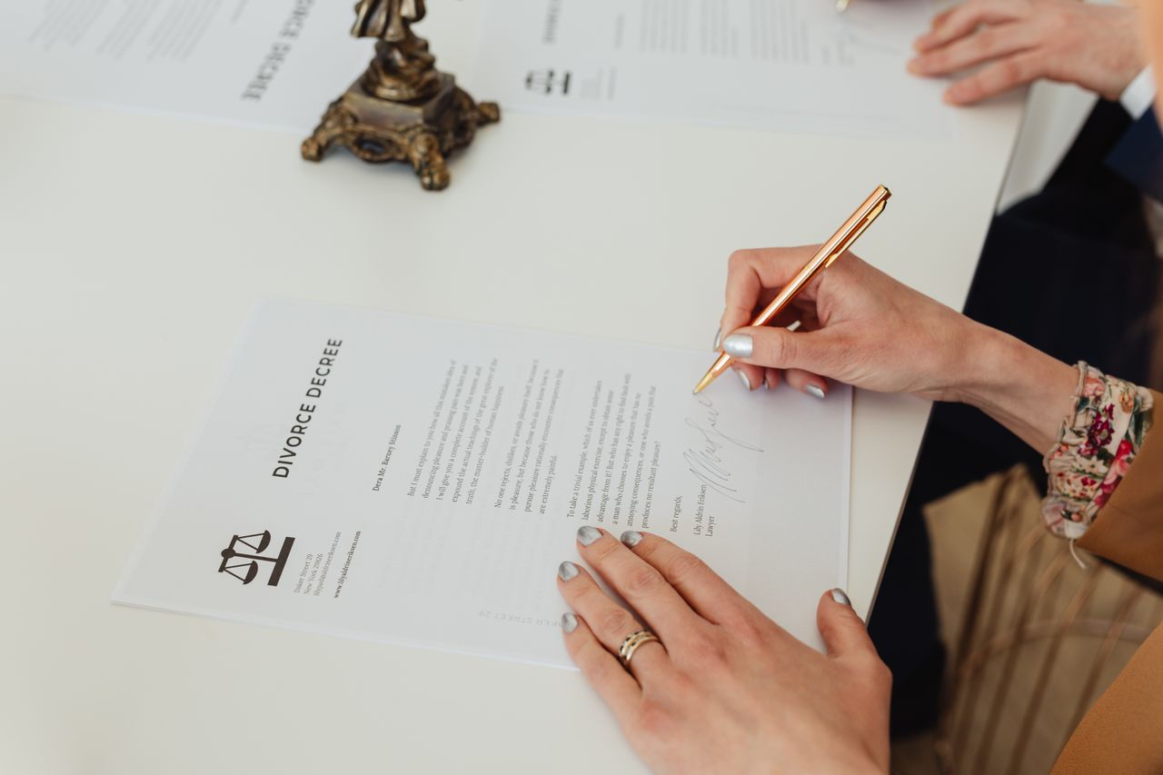 Certificaciones, Poderes y Ratificaciones Close-up of hands signing a divorce decree document on a desk, showcasing legal process.
