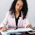 Focused businesswoman signing important documents at her office desk.